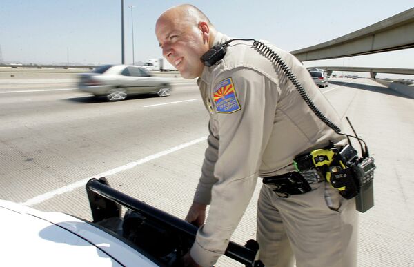 An Arizona Department of Public Safety officer adjusts the infrared license plate scanner mounted on the front bumper of his police cruiser along the I-10 in Phoenix. - Sputnik International