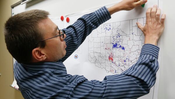 In this June 26, 2014 file photo, Austin Holland, research seismologist at the Oklahoma Geological Survey, hangs up a chart depicting earthquake activity at their offices at the University of Oklahoma in Norman, Okla. A study published Thursday, July 3, 2014 by the journal Science explains how just four wells forcing massive amounts of drilling wastewater into the ground are probably causing quakes in Oklahoma. The wells seem to have triggered more than 100 small-to-medium earthquakes in the past five years, according to a study. - Sputnik International