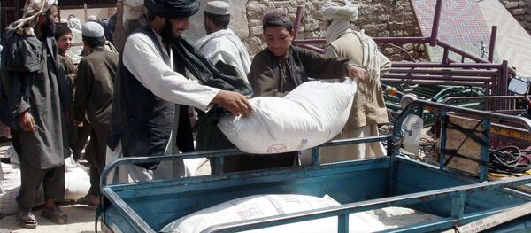 Afghans put a sack of wheat on the carrier back of a motor bike during a food distribution to displaced families from Helmand province. Afghans put a sack of wheat on the carrier back of a motor bike during a food distribution to displaced families from Helmand province. - Sputnik International
