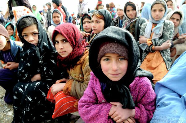 Village girls wait as humanitarians unload a shipment of food, clothing and supplies in western Afghanistan. - Sputnik International
