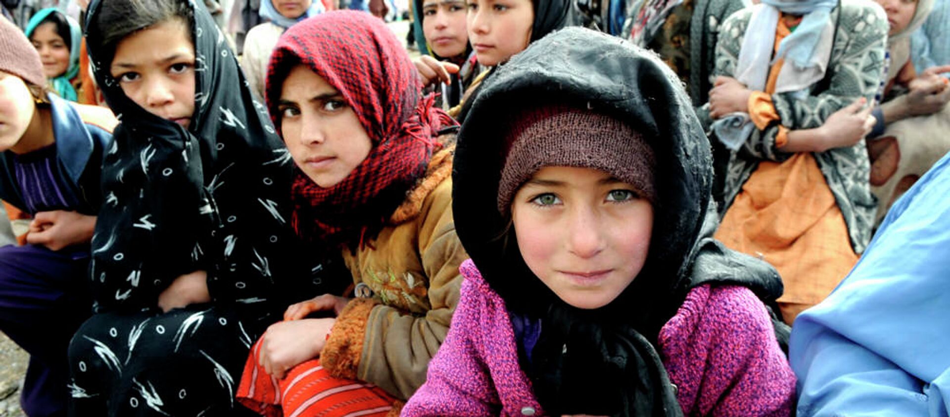 Village girls wait as humanitarians unload a shipment of food, clothing and supplies in western Afghanistan. - Sputnik International, 1920, 13.08.2021