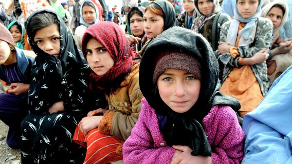 Village girls wait as humanitarians unload a shipment of food, clothing and supplies in western Afghanistan. - Sputnik International