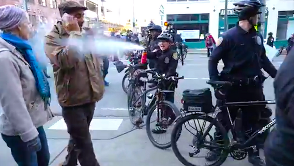 In this screenshot from a YouTube video, a Seattle police officer pepper-sprays school teacher Jesse Hagopian following a Martin Luther King Jr. Day rally. - Sputnik International