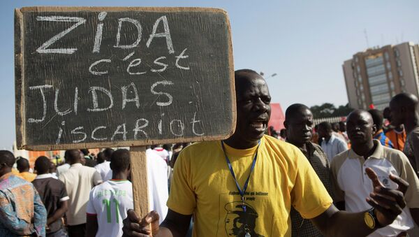 A protester carries a sign reading Zida is Judas Iscariot, referring to coup leader Lt. Col. Yacouba Isaac Zida, in Ouagadougou, capital of Burkina Faso - Sputnik International