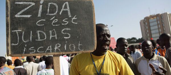 A protester carries a sign reading Zida is Judas Iscariot, referring to coup leader Lt. Col. Yacouba Isaac Zida, in Ouagadougou, capital of Burkina Faso - Sputnik International