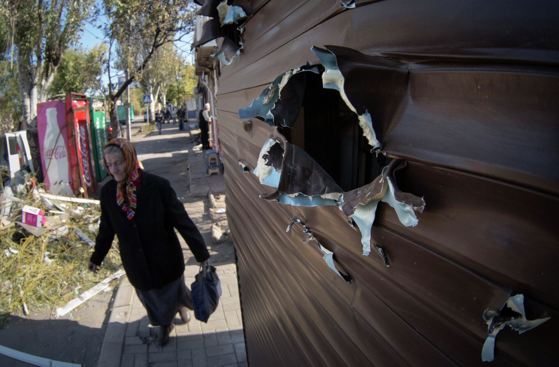 An elderly woman walks past a kiosk damaged by shrapnel at a street market after shelling in the town of Donetsk, eastern Ukraine Friday, Oct. 10, 2014 - Sputnik International, 1920, 18.02.2024