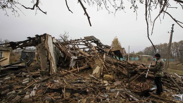 Vladimir Shramko, 48, checks debris of his neighbor's house, which was damaged by shelling in the village of Spartak, on the outskirts of Donetsk, eastern Ukraine - Sputnik International