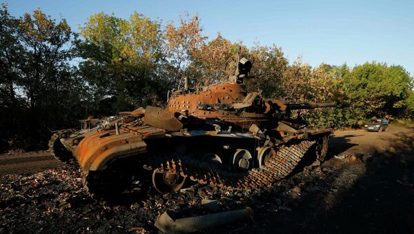 A car passes by a destroyed Ukrainian tank near the village of Dmytrivka in eastern Ukraine - Sputnik International