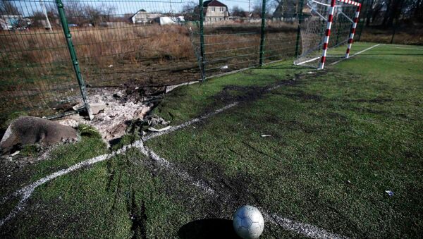 A ball is seen near a crater caused by shelling at a school's soccer field in Donetsk, eastern Ukraine. - Sputnik International