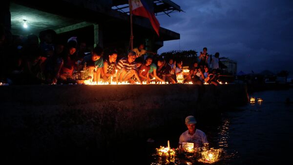 Typhoon survivors light candles to commemorate the victims who perished during the onslaught of Typhoon Haiyan a year ago in Tacloban city - Sputnik International