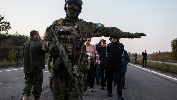 A Ukrainian soldier (C) stands guard as members of the eastern Ukrainian militia, who are prisoners-of-war (POWs), walk along a road as they wait to be exchanged, north of Donetsk, eastern Ukraine, September 28, 2014 - Sputnik International
