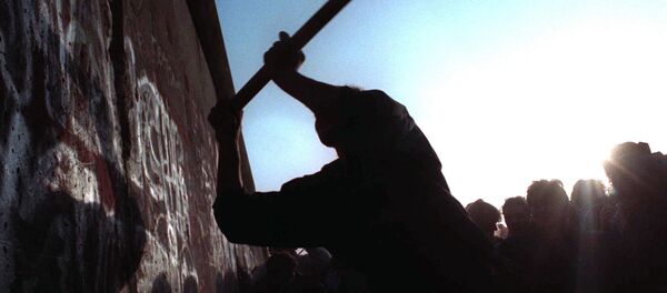 A man hitting a segment of the Berlin Wall with a hammer. - Sputnik International