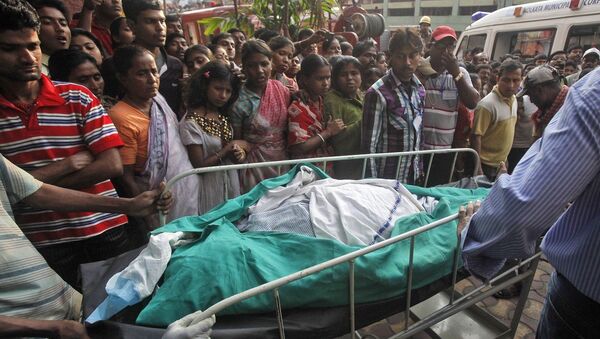 People watch as the body of a victim of a fire is wheeled towards an ambulance outside a private hospital in Kolkata, India, Friday, Dec. 9, 2011 - Sputnik International