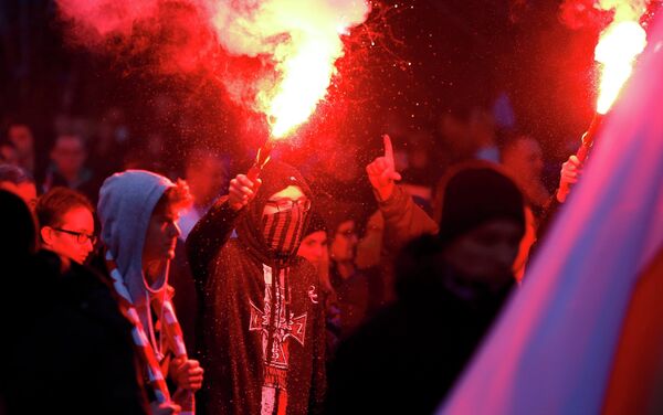 A protester holds a flare as several hundred masked men broke away from a far-right march and threw stones and flares at lines of riot police in Warsaw November 11, 2014 - Sputnik International