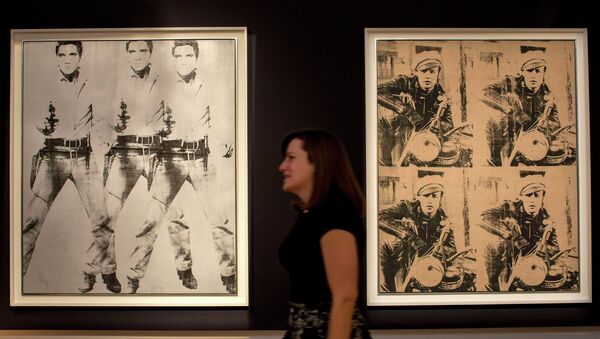 A woman walks between Triple Elvis and Four Marlons by Andy Warhol during a media preview at Christie's auction house in New York - Sputnik International