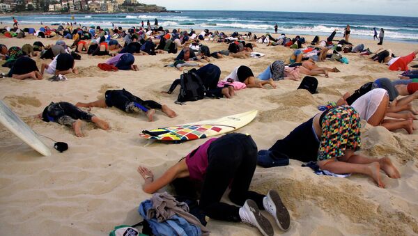 A group of around 400 demonstrators participate in a protest by burying their heads in the sand at Sydney's Bondi Beach - Sputnik International