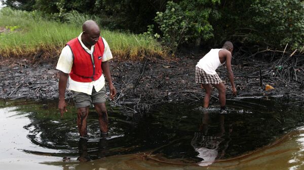 In this June 20, 2010 file photo, men walk in an oil slick covering a creek near Bodo City in the oil-rich Niger Delta region of Nigeria - Sputnik International