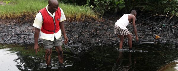 In this June 20, 2010 file photo, men walk in an oil slick covering a creek near Bodo City in the oil-rich Niger Delta region of Nigeria In this June 20, 2010 file photo, men walk in an oil slick covering a creek near Bodo City in the oil-rich Niger Delta region of Nigeria - Sputnik International