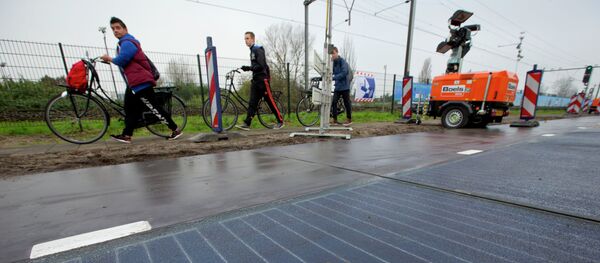Bicyclists are forced to use the sidewalk as they pass a stretch of bicycle path where a solar panel roadway is being constructed in Krommenie, north of Amsterdam, Netherlands, Tuesday, Nov. 11, 2014 - Sputnik International