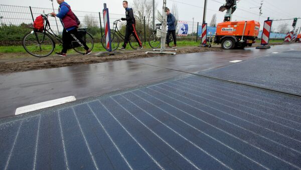 Bicyclists are forced to use the sidewalk as they pass a stretch of bicycle path where a solar panel roadway is being constructed in Krommenie, north of Amsterdam, Netherlands, Tuesday, Nov. 11, 2014 - Sputnik International