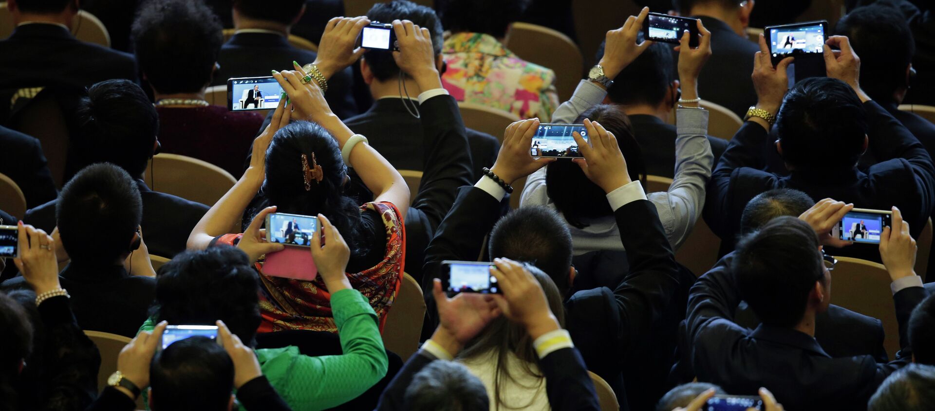Delegates use their smartphones to take pictures of Russian President Vladimir Putin speaks during a dialogue session with delegates during the APEC CEO Summit - Sputnik International, 1920, 11.03.2021