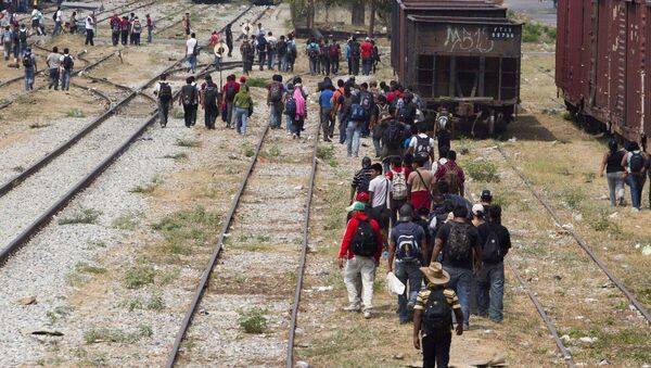 Immigrants walk along the rail tracks after getting off a train during their journey toward the US-Mexico border in Ixtepec, southern Mexico - Sputnik International