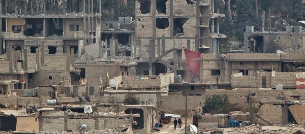Kurdish fighters walk between damaged buildings - Sputnik International