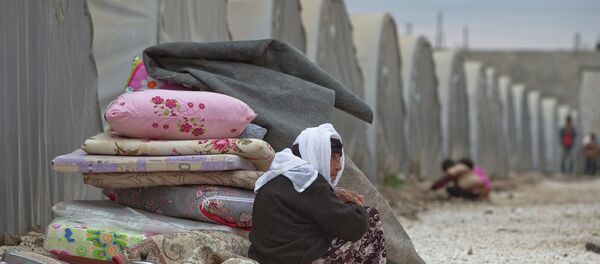 A Syrian Kurdish refugee woman from the Kobani area sits next to belongings on a cold morning at a camp in Suruc, on the Turkey-Syria border Monday, Nov. 17, 2014. A Syrian Kurdish refugee woman from the Kobani area sits next to belongings on a cold morning at a camp in Suruc, on the Turkey-Syria border Monday, Nov. 17, 2014. - Sputnik International