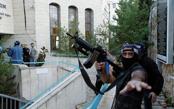 An Israeli police officer gestures as he holds a weapon near the scene of an attack at a Jerusalem synagogue. - Sputnik International