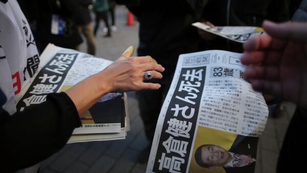 A worker, bottom, distributes an extra edition of a newspaper with front page featuring an obituary notice of acclaimed Japanese film star Ken Takakura at Shimbashi Station in Tokyo, Tuesday, Nov. 18, 2014 - Sputnik International