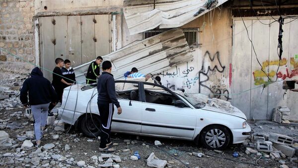 Palestinians stand next to a car damaged during the demolition of Abdel-Rahman Shaloudi's home in the East Jerusalem neighbourhood of Silwan November 19, 2014 - Sputnik International