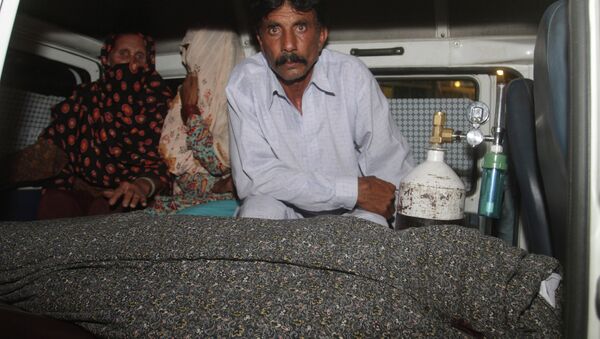 Mohammad Iqbal, right, husband of Farzana Parveen, 25, sits in an ambulance next to the body of his pregnant wife who was stoned to death by her own family, in Lahore, Pakistan, Tuesday, May 27, 2014 - Sputnik International