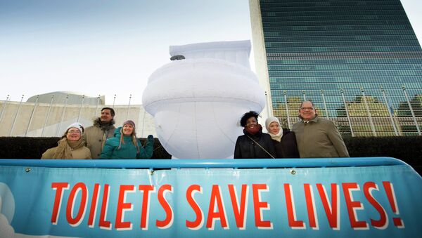 A small group of UN staff, with a “Toilets Save Lives!” banner, poses for a photo with a 15-foor-high inflatable toilet, in front of United Nations headquarters - Sputnik International