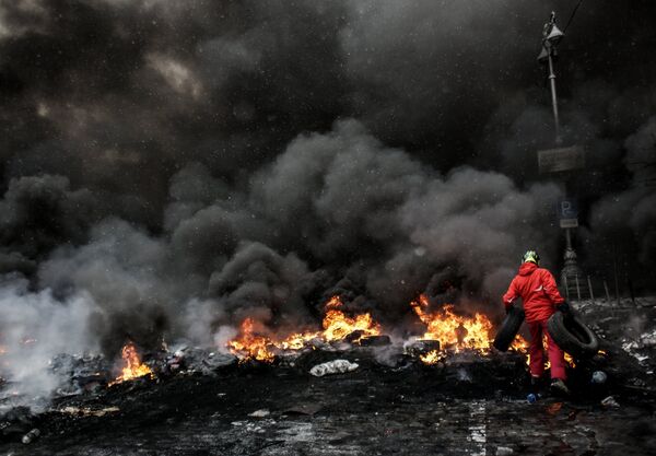 A protester adds tire to the fire in Maidan square in Kiev, Ukraine, Jan 22, 2014  - Sputnik International
