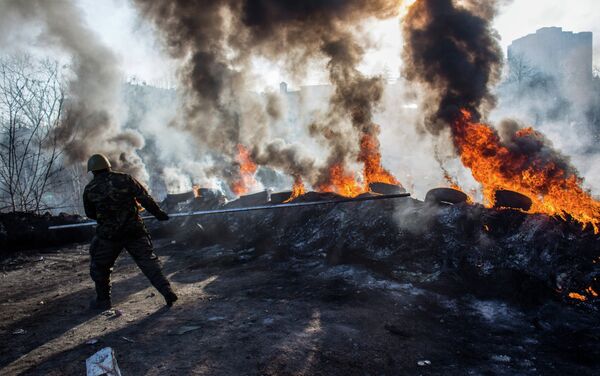 A radical opposition member rolls tires into flames on Institutskaya Street, Kiev. - Sputnik International