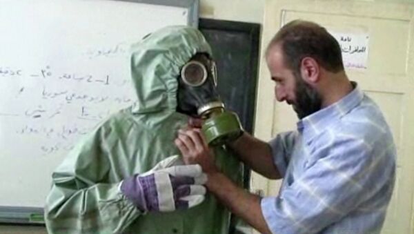 Volunteer adjusting a gas mask and protective suit on a student during a classroom session a on how to respond to a chemical weapons attack in Aleppo, Syria - Sputnik International