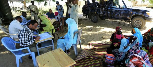 Special Prosecutor for Crimes in Darfur Yasir Ahmed Mohamed (back, in blue shirt with glasses) and his team talk to women during an investigation into allegations of mass rape in the village of Tabit Special Prosecutor for Crimes in Darfur Yasir Ahmed Mohamed (back, in blue shirt with glasses) and his team talk to women during an investigation into allegations of mass rape in the village of Tabit - Sputnik International