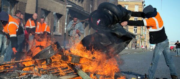 A man throws rubber tires onto a fire during a demonstration in the Port of Antwerp in Antwerp, Belgium A man throws rubber tires onto a fire during a demonstration in the Port of Antwerp in Antwerp, Belgium - Sputnik International