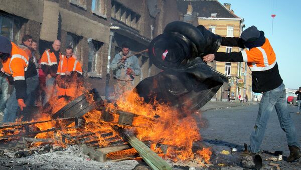A man throws rubber tires onto a fire during a demonstration in the Port of Antwerp in Antwerp, Belgium - Sputnik International