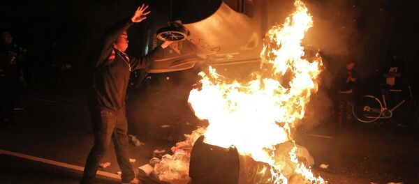 A protester throws a trash can on a fire during a demonstration in Oakland, California following the grand jury decision in the shooting of Michael Brown in Ferguson, Missouri - Sputnik International