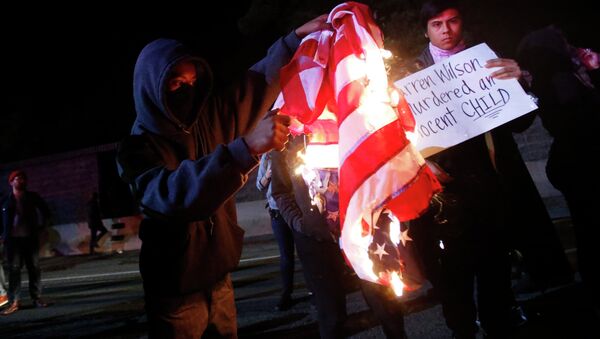 A protester burns an American flag on Highway 580 during a demonstration following the grand jury decision in the Ferguson, Missouri shooting of Michael Brown, in Oakland, California - Sputnik International