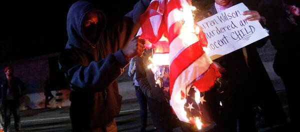 A protester burns an American flag on Highway 580 during a demonstration following the grand jury decision in the Ferguson, Missouri shooting of Michael Brown, in Oakland, California - Sputnik International