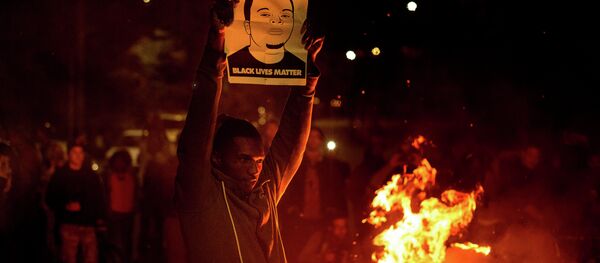 A demonstrator holds a protest sign in Oakland - Sputnik International