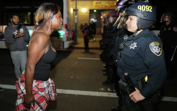 Amanda Ashe of Oakland, left, faces off with a police officer during the second night of demonstrations in Emeryville, California, following the grand jury decision in the shooting of Michael Brown in Ferguson, Missouri - Sputnik International