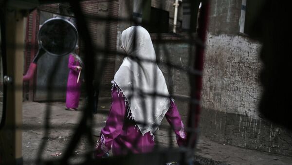 An Egyptian woman seen from a motorized rickshaw walks on a street, near the home of 13-year-old Sohair el-Batea who died undergoing the procedure of female genital mutilation - Sputnik International