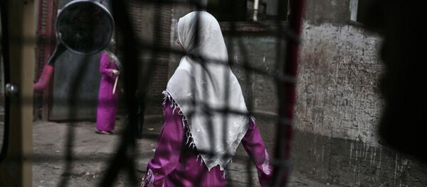 An Egyptian woman seen from a motorized rickshaw walks on a street, near the home of 13-year-old Sohair el-Batea who died undergoing the procedure of female genital mutilation - Sputnik International