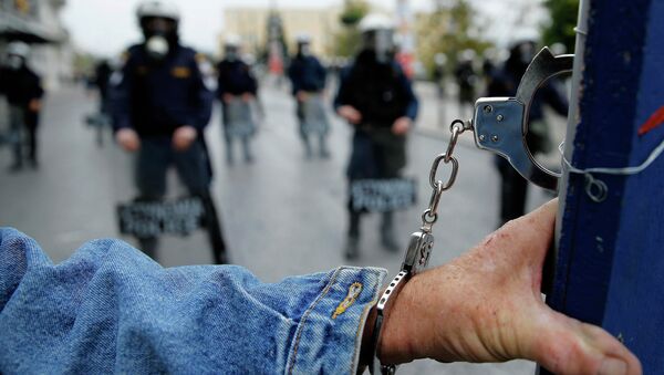 A protester wears handcuffs as he stands in front of riot police following a march during a 24-hour general strike in central Athens November 27, 2014 - Sputnik International
