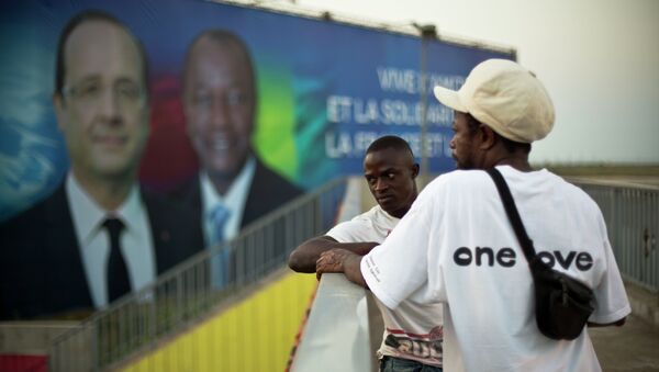 Two Guinean men stand on a pedestrian overpass near the People's Palace where a giant billboard featuring French President Francois Hollande - Sputnik International