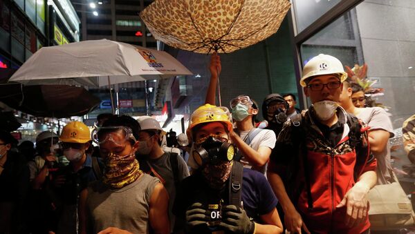 Protesters protect themselves from being sprayed with tear spray during a confrontation with riot police at Mongkok shopping district in Hong Kong - Sputnik International