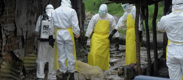 Health workers wearing protective clothing prepare to carry an abandoned dead body presenting with Ebola symptoms at Duwala market in Monrovia - Sputnik International